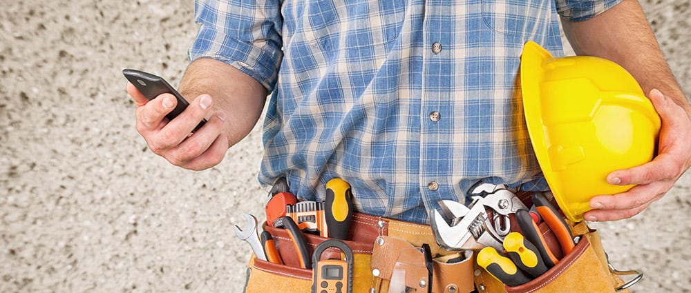 construction worker with tool belt holding hard hat and accessing SecureCore disaster plan on a cell phone